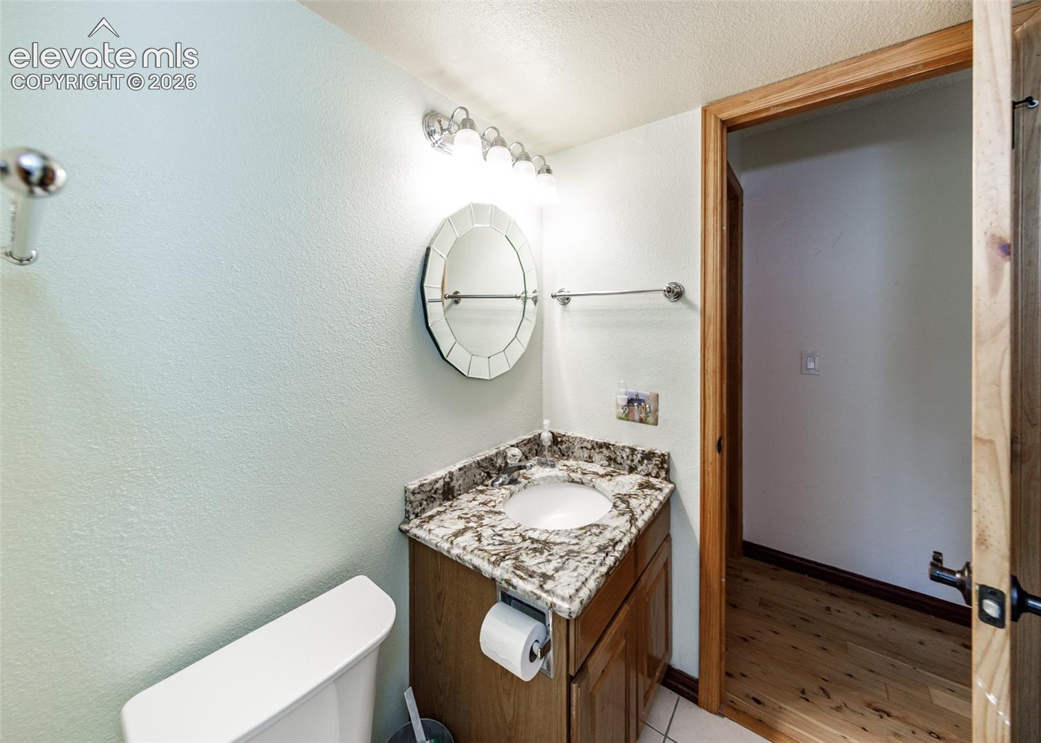 Vanity with granite-style countertop, integrated sink, and wood cabinetry