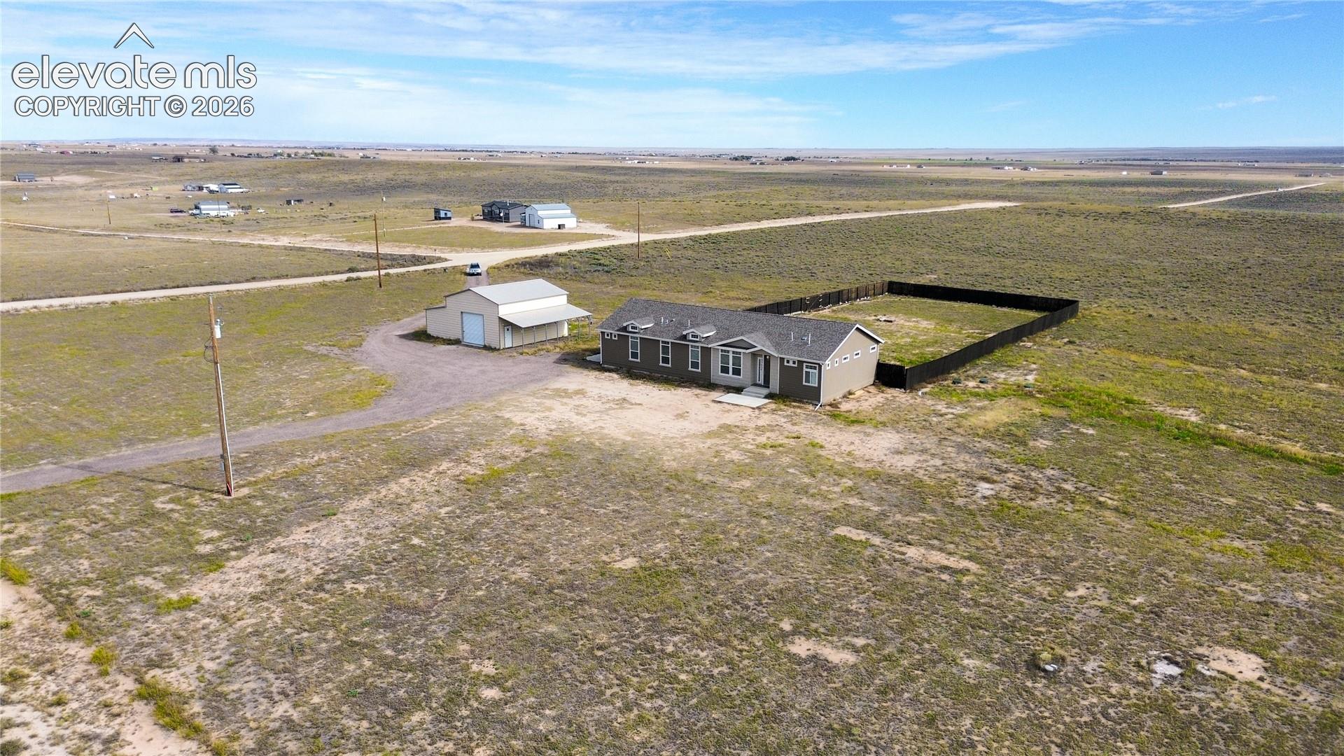 Single-level residence featuring an attached garage, a detached workshop, and a fenced exterior area, all situated on expansive acreage