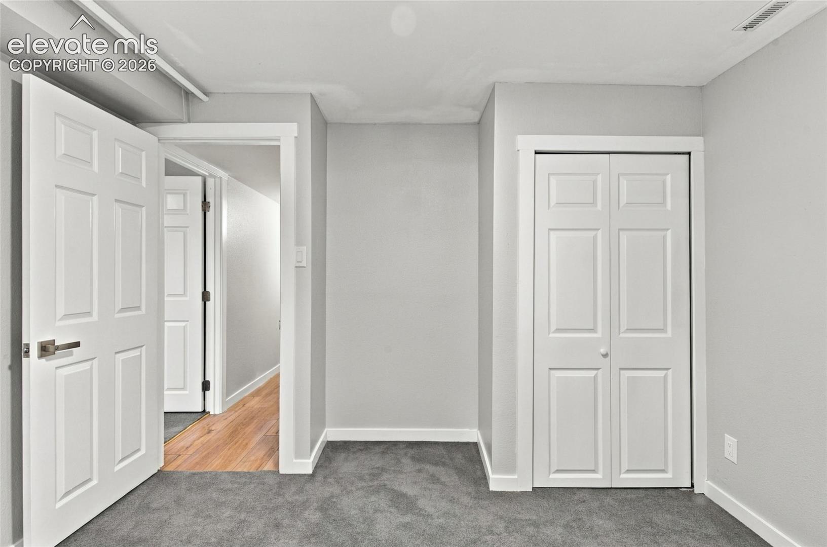 Interior space featuring neutral wall paint, carpeted flooring, a closet with bi-fold panel doors, and solid-core paneled interior doors