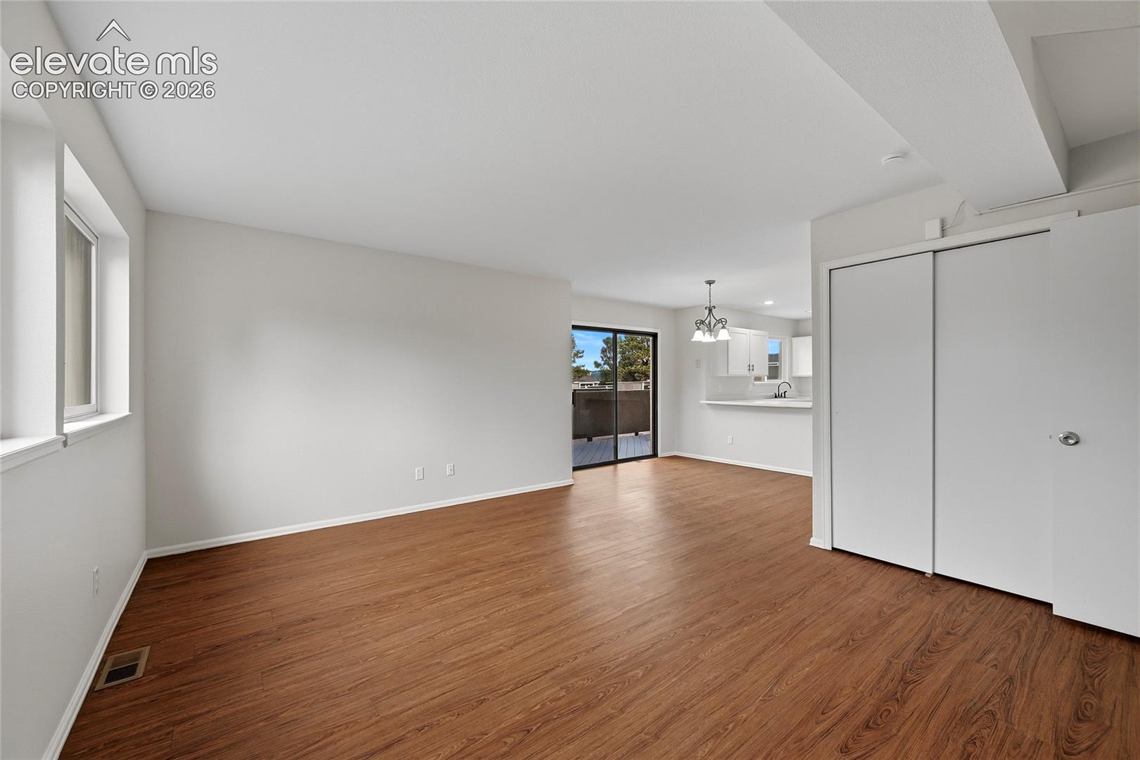 Open-concept interior featuring wood-finish flooring, sliding glass patio door, and a built-in closet with sliding doors