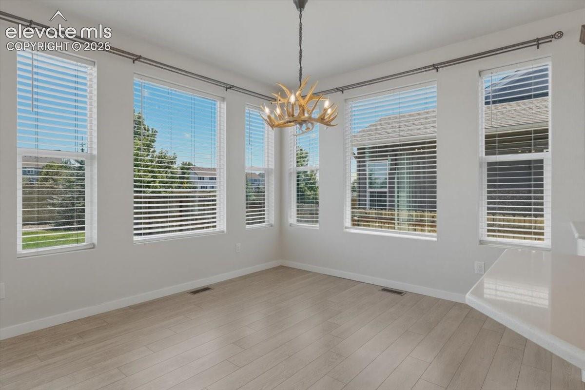 Open dining area featuring light wood-finish flooring and a prominent antler-style chandelier