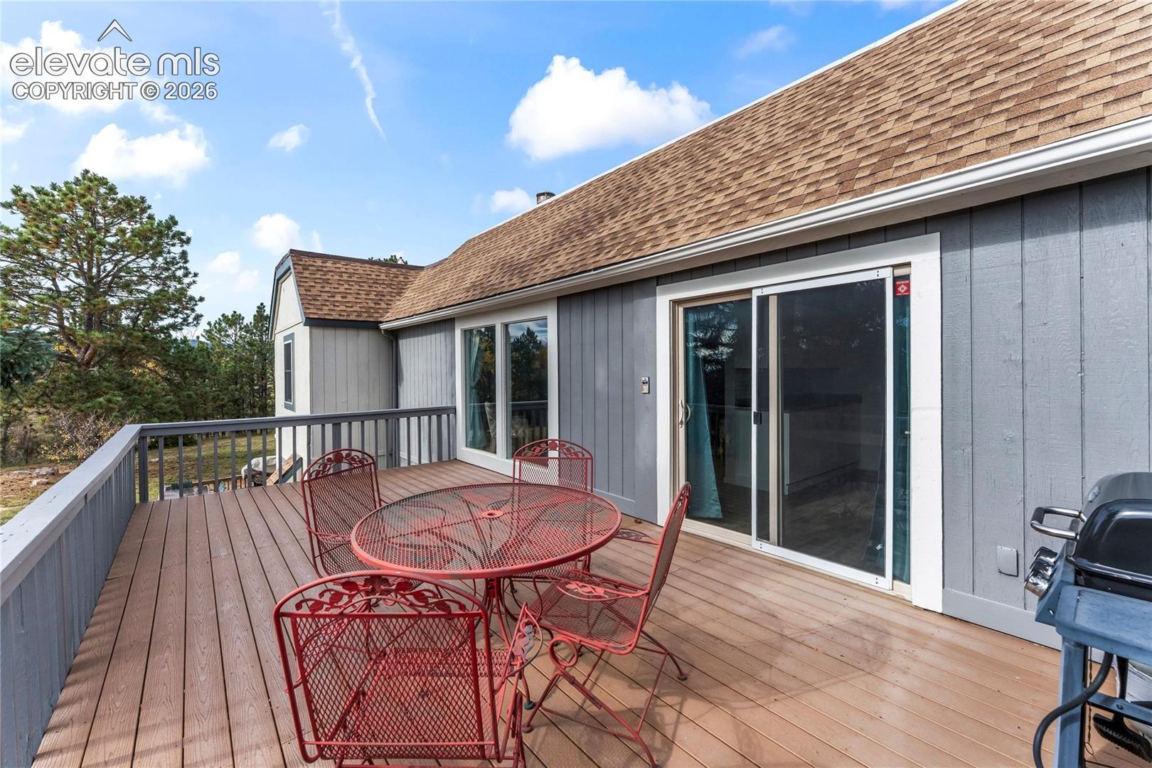 Elevated deck with composite wood-finish decking, vertical siding, and glass sliding doors
