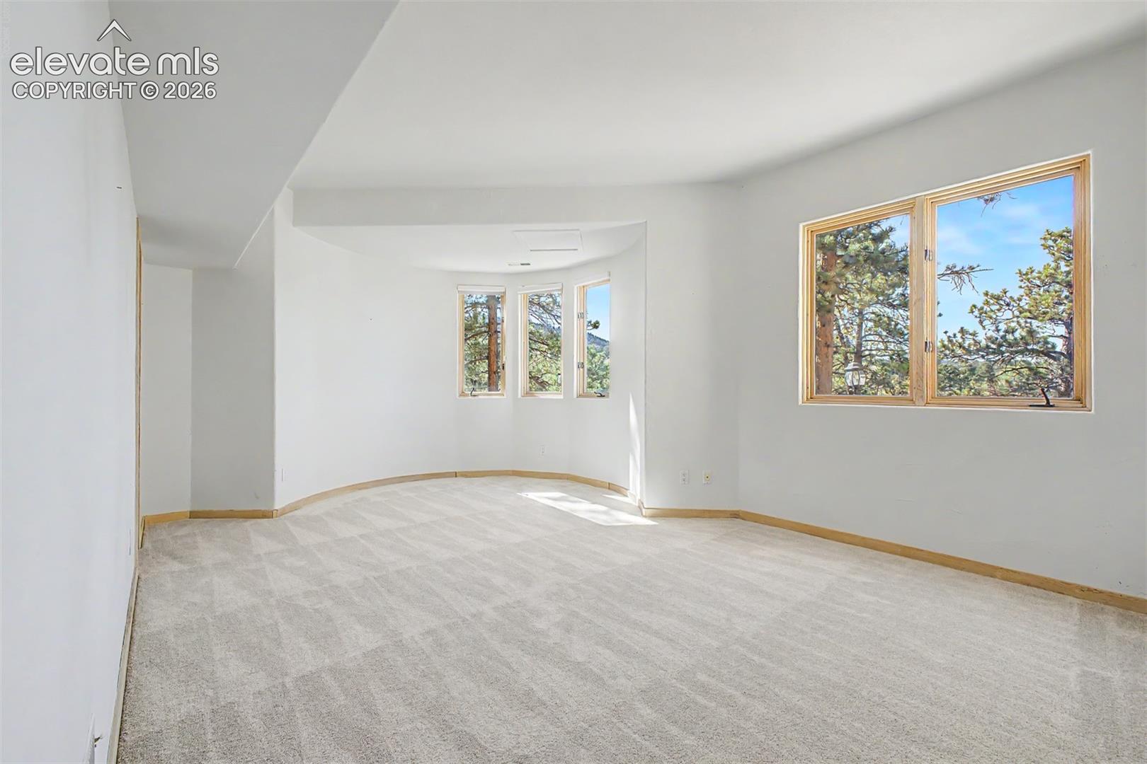 Spacious room with light-toned patterned carpeting and multiple large windows