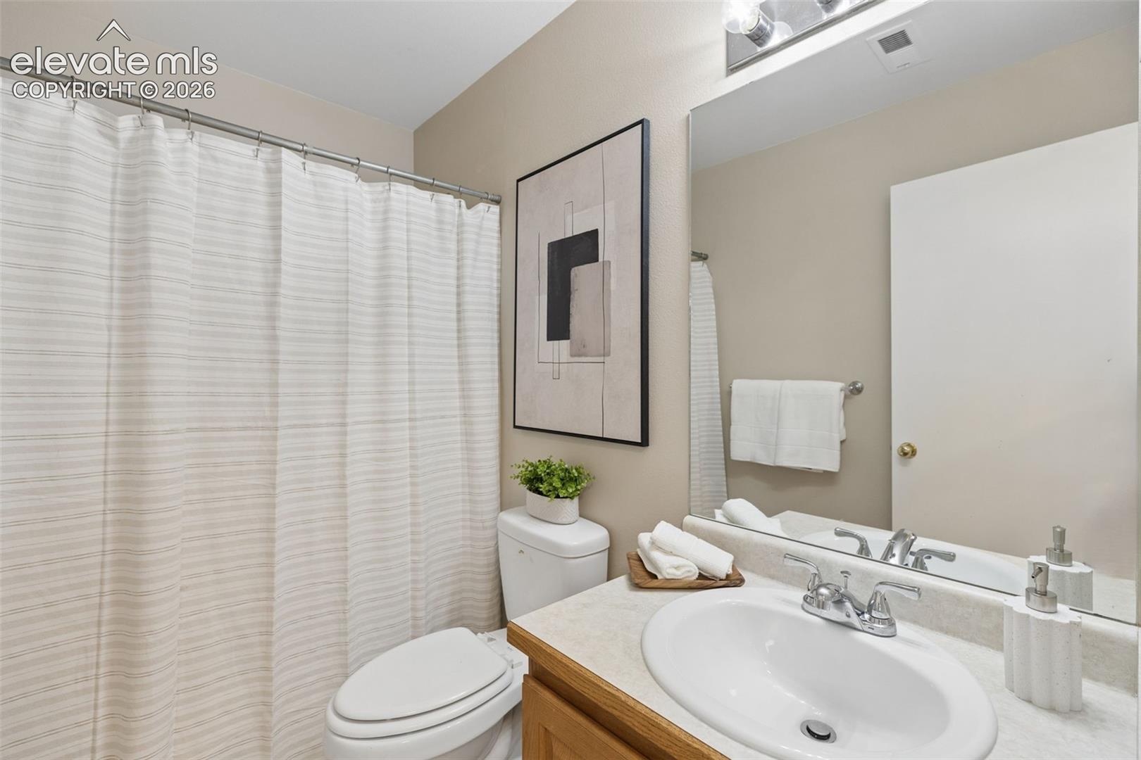 Bathroom featuring a vanity with a drop-in sink, chrome fixtures, a large wall-mounted mirror, and a shower-tub combination