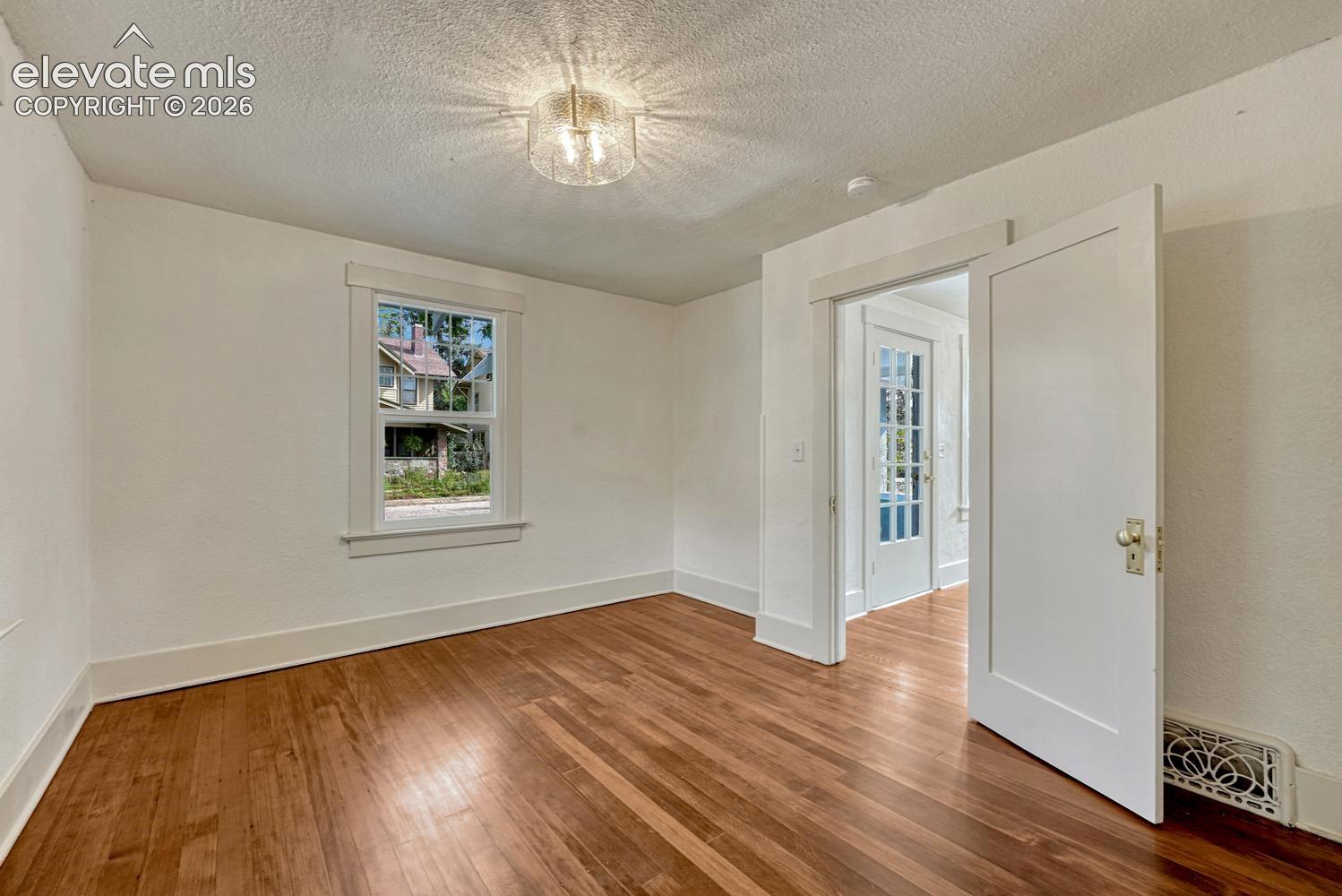 Wood-finish flooring, white trim, and a frosted glass ceiling light fixture