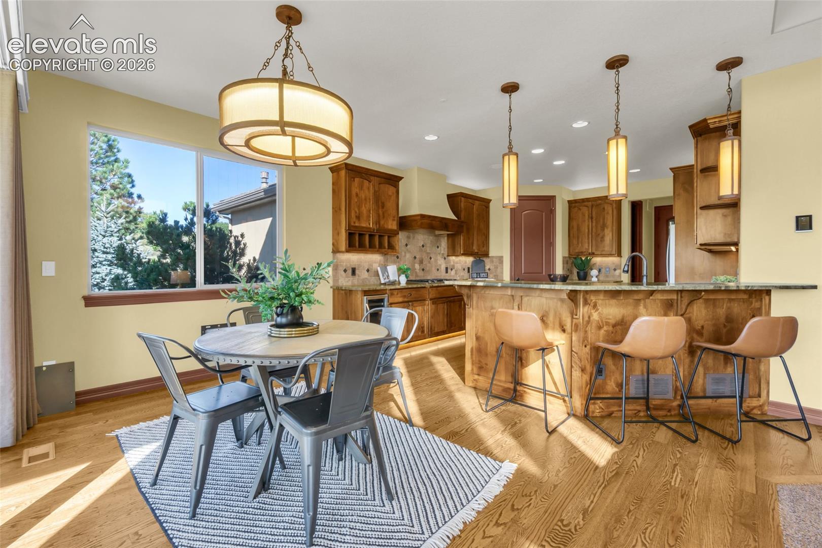 Open-concept kitchen and dining area featuring custom wood cabinetry, stainless steel appliances, and a large island with seating