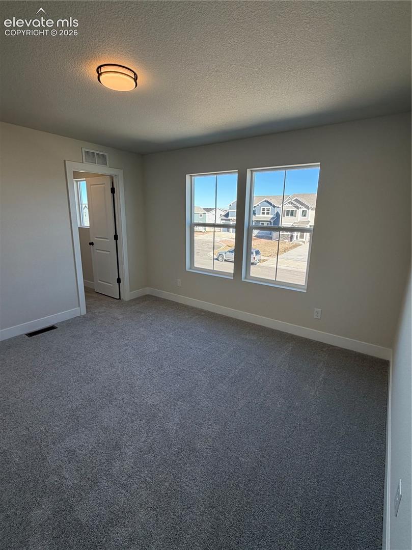 Neutral-toned interior featuring wall-to-wall carpeting, dual paned windows, and a flush-mount overhead light fixture