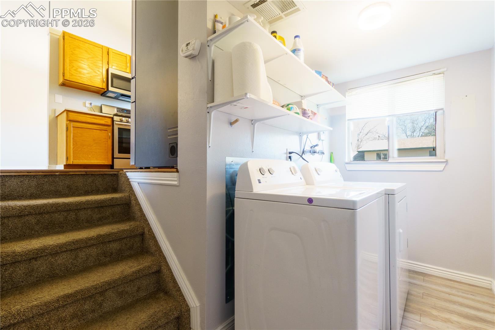 Clothes washing area featuring laundry area, separate washer and dryer, visible vents, light wood finished floors, and baseboards