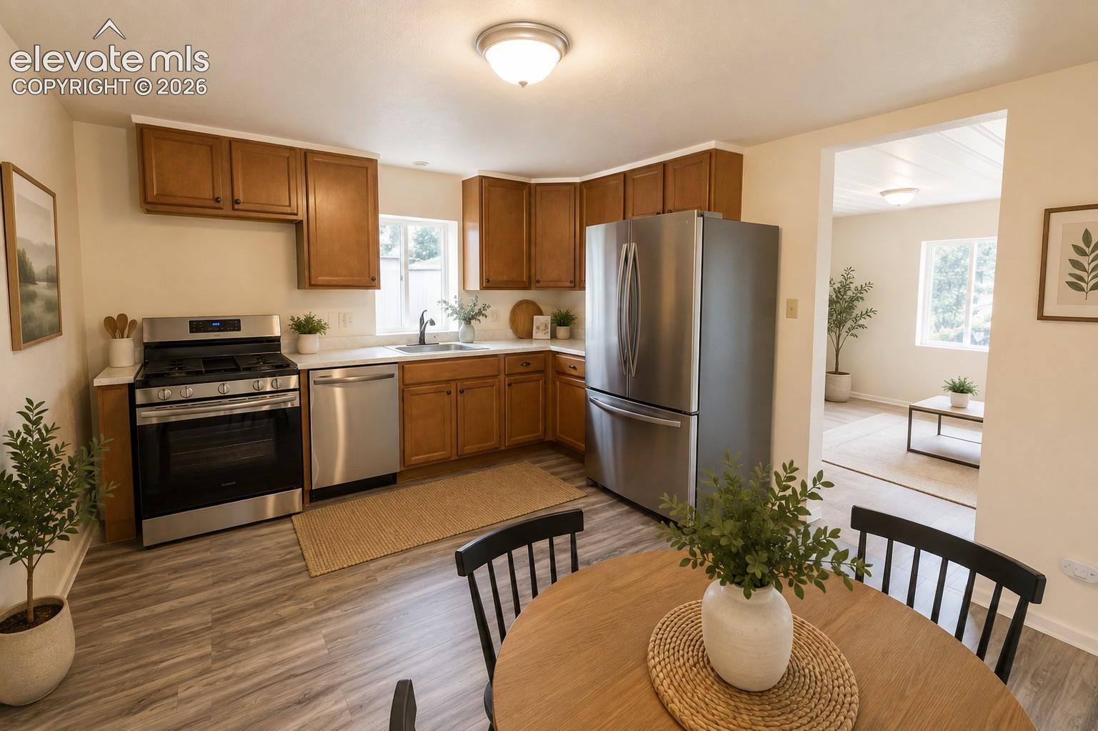 Kitchen featuring medium-tone wood cabinetry, stainless steel appliances, white countertops, and wood-finish flooring