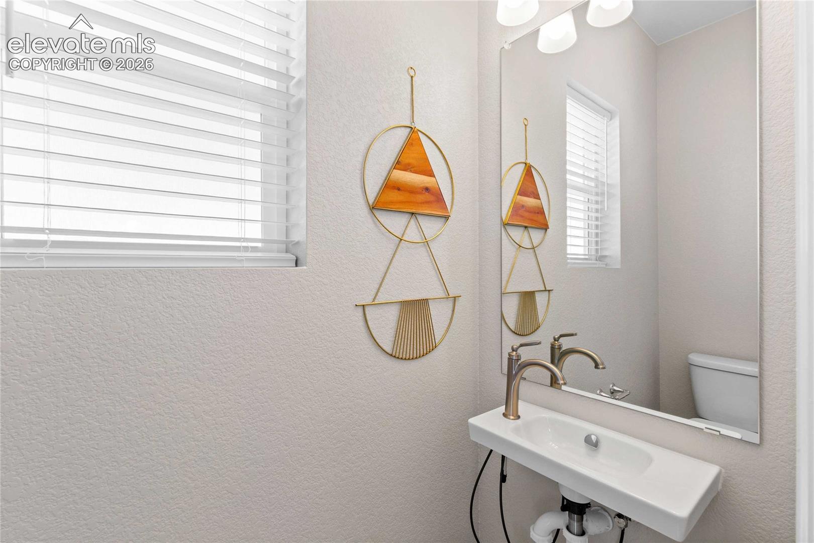 Pedestal sink with a single-handle faucet, full-length wall mirror, and window with blinds
*photos of a model home*