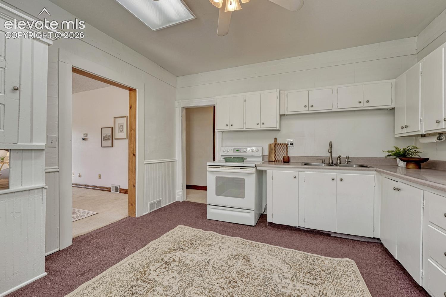 White cabinetry and appliances, double basin sink with high-arc faucet, and built-in ceiling lighting