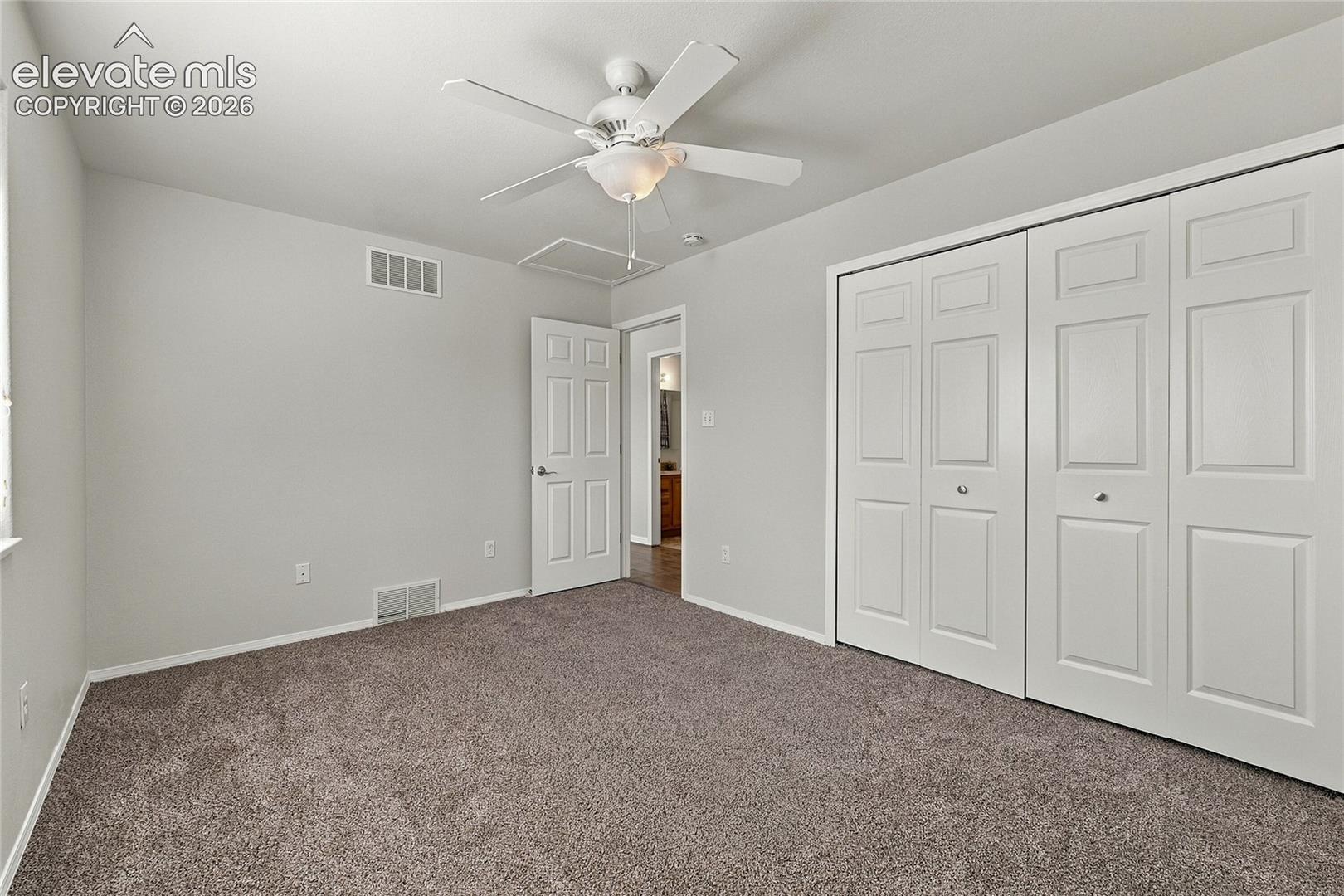 Carpeted interior featuring a ceiling fan with integrated lighting and double-panel closet doors