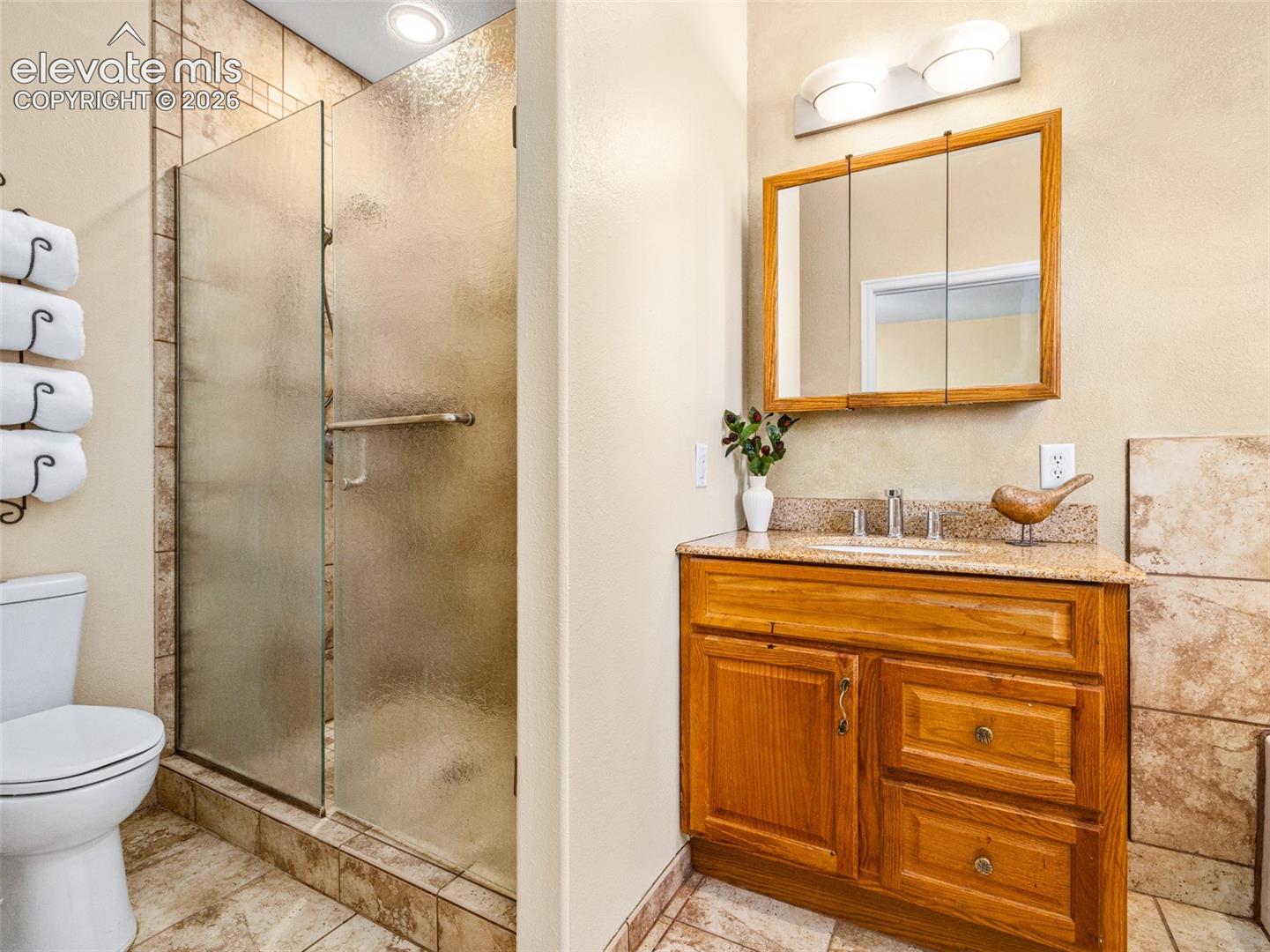 Walk-in shower with frosted glass enclosure, tile surround, and recessed lighting