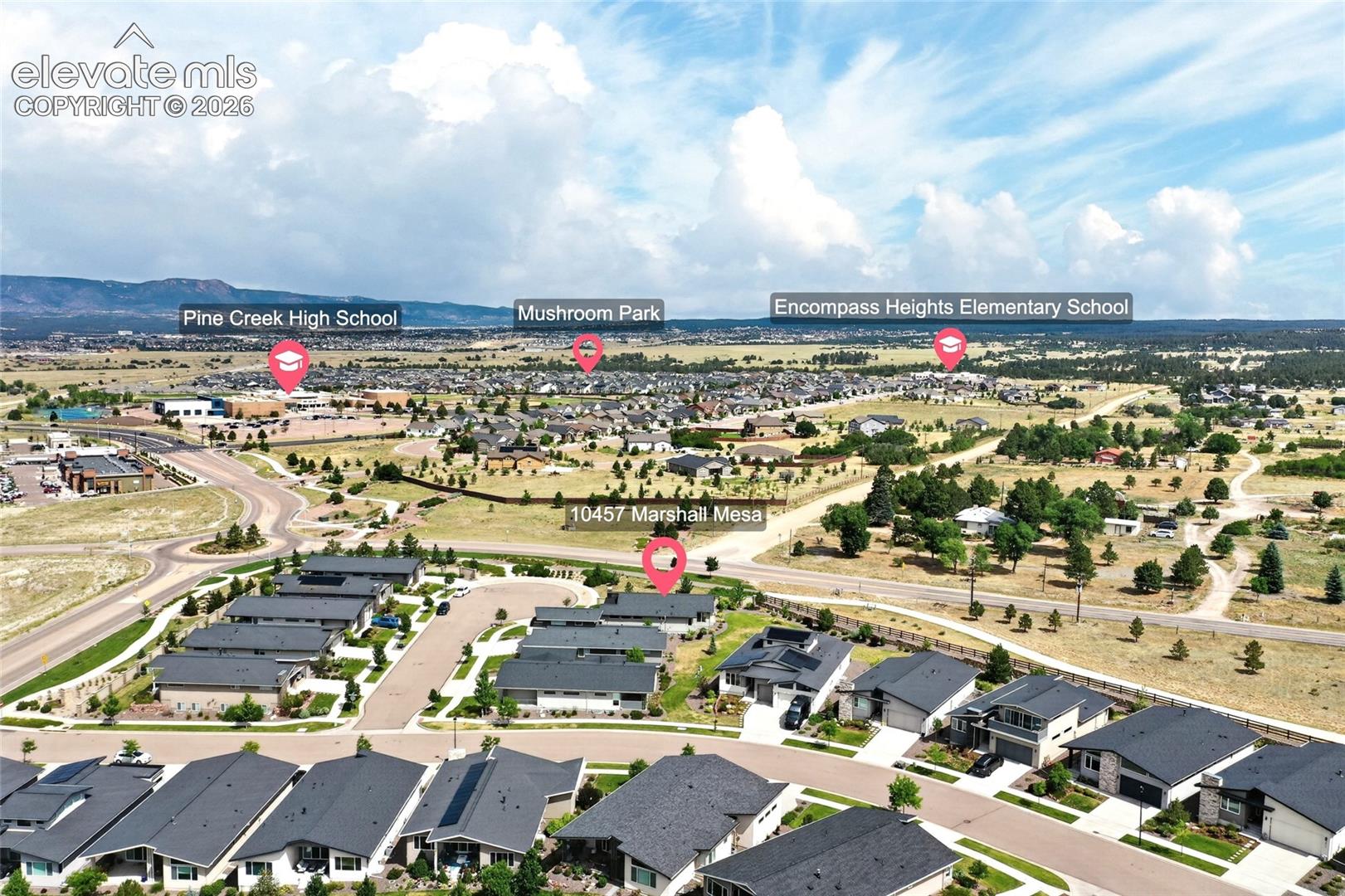 Aerial perspective showcasing a residential community with contemporary homes, paved roadways, and surrounding natural landscapes