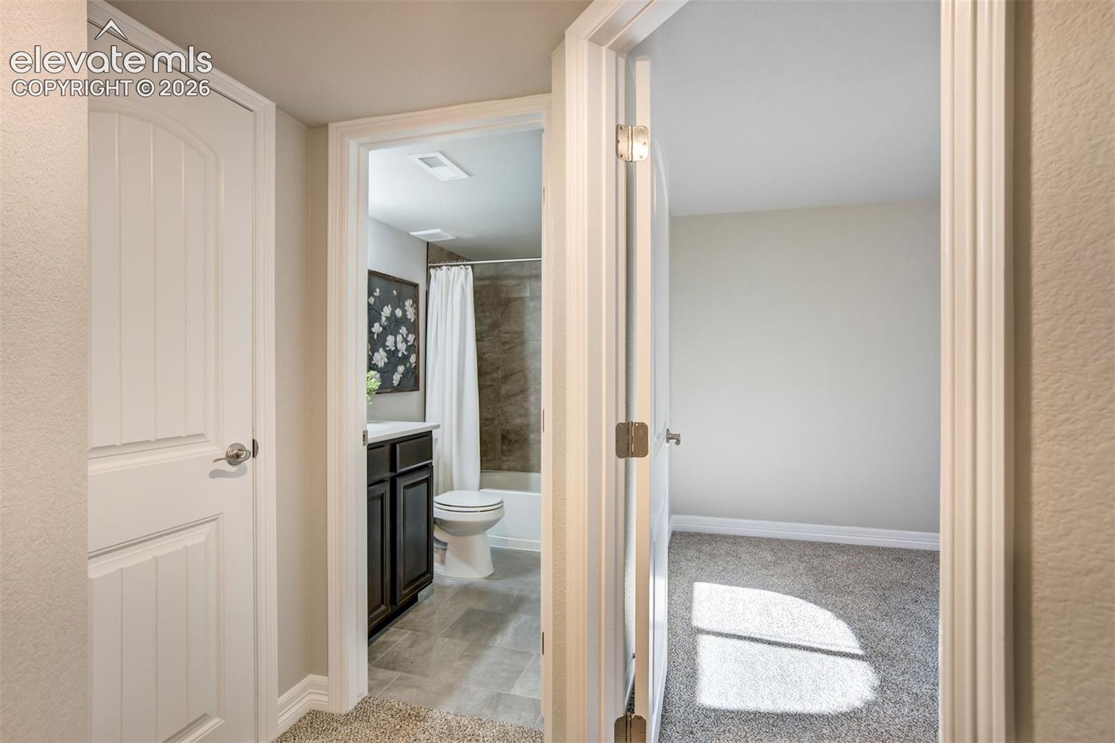 Bathroom with dark wood-finish vanity and tiled shower surround