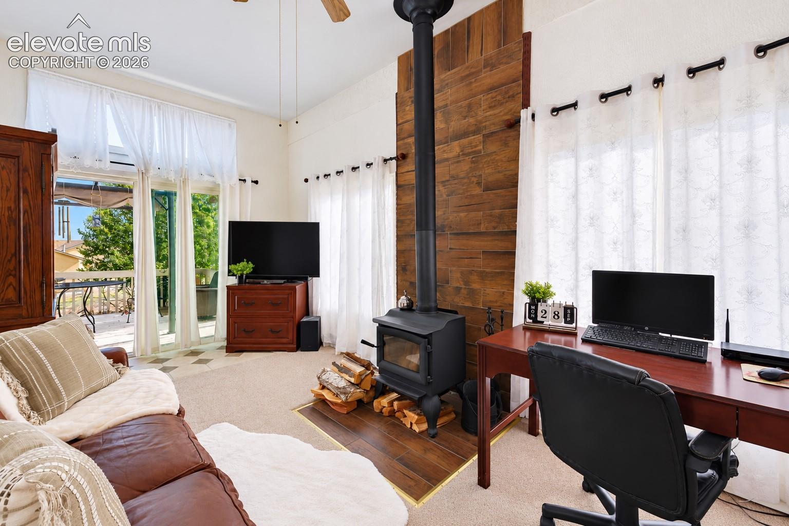 Freestanding black cast-iron wood stove, full-height decorative wood-finish wall paneling, tile hearth, sliding glass door, and ceiling fan