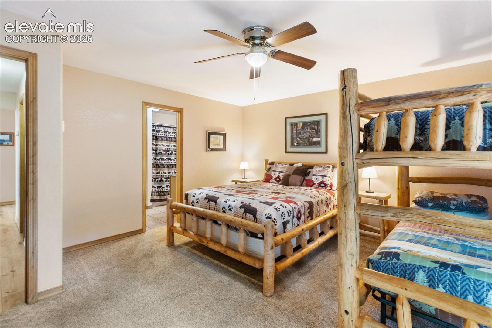 Neutral tone wall color, carpeted flooring, wood-finish trim, ceiling fan, and interior doorway with wood-finish casing