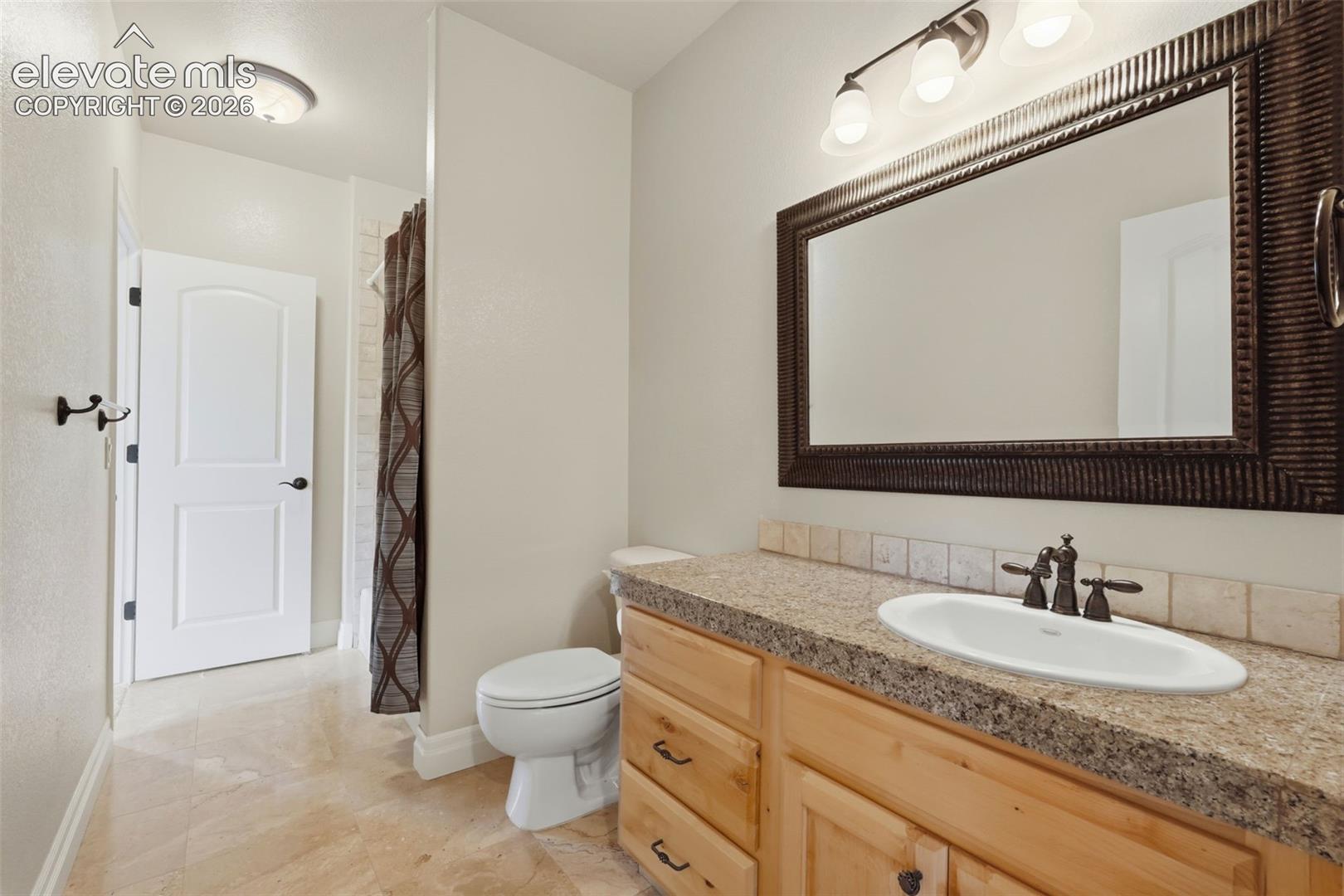 Bathroom vanity with a granite-look countertop, integrated oval sink, and bronze-finish faucet