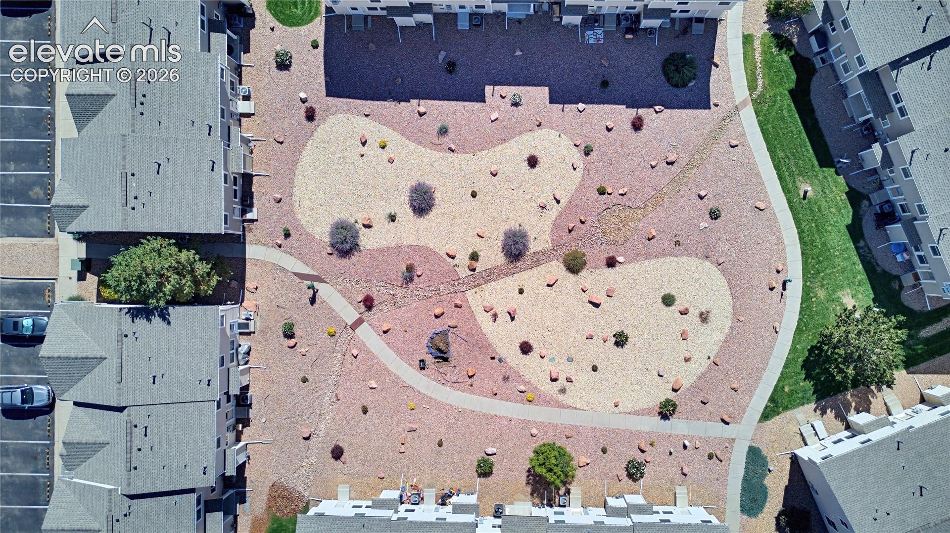 Landscaped courtyard featuring a meandering path, varied shrubbery, and decorative rock elements