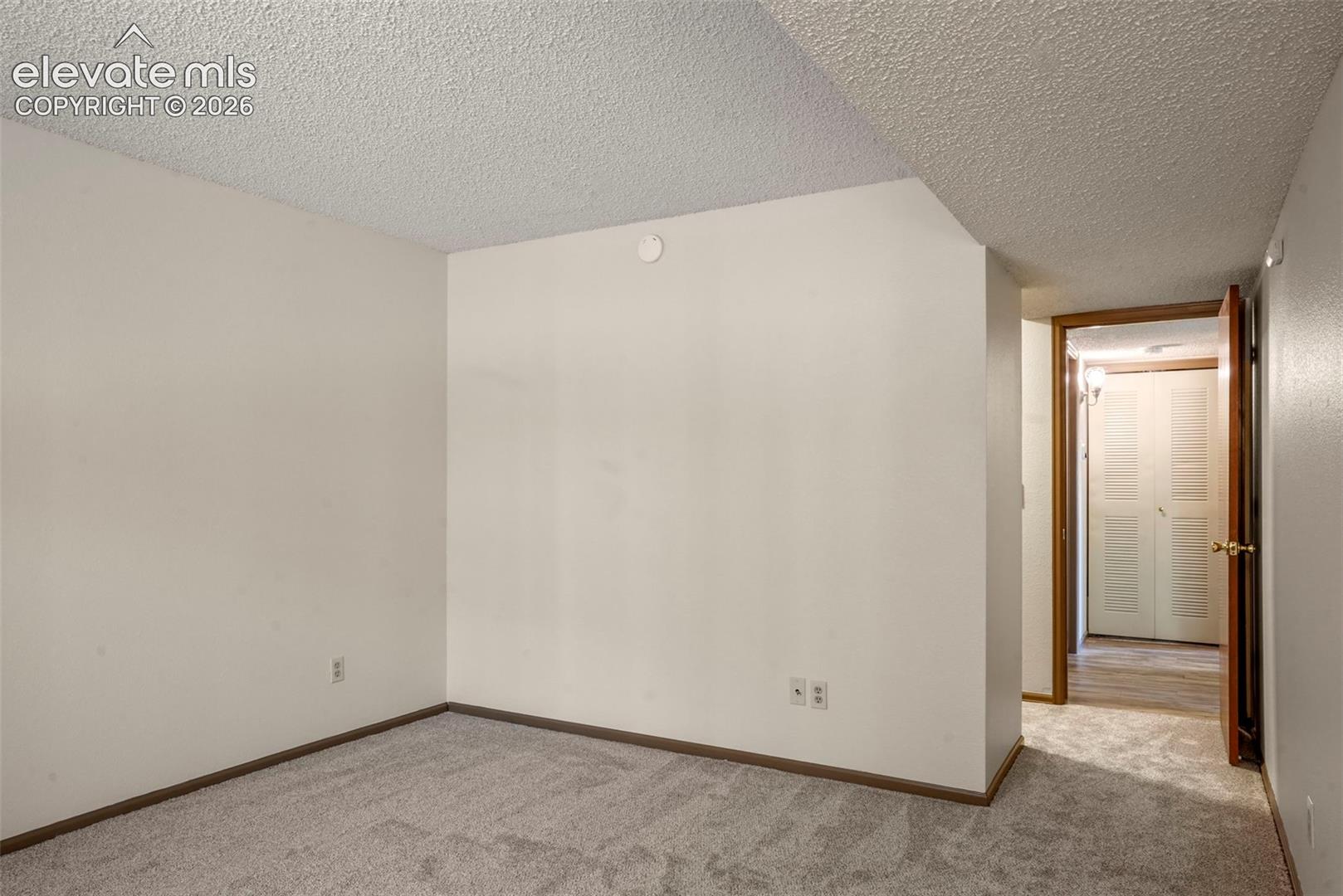 Spare room featuring light carpet and a textured ceiling