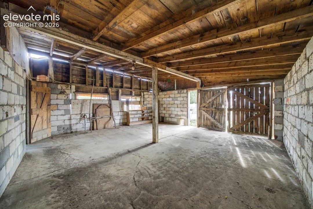 Concrete flooring, exposed wood beam ceiling, block wall construction, wood-plank doors