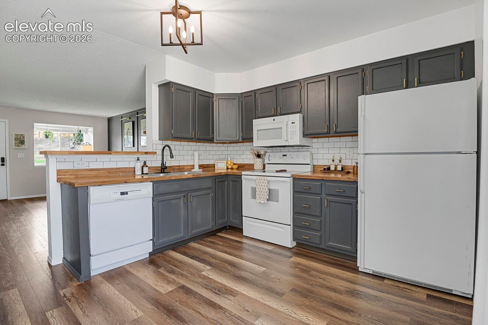 L-shaped kitchen with wood-finish flooring, grey cabinetry, wood-look countertops, and white subway tile backsplash