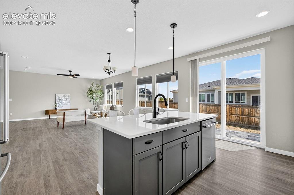 Kitchen island with quartz countertop and undermount sink, complemented by pendant lighting