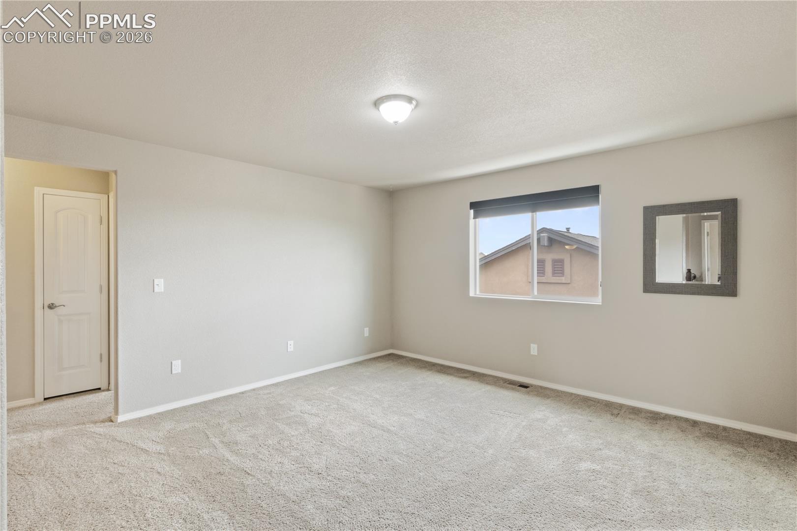 Unfurnished room featuring light colored carpet and a textured ceiling