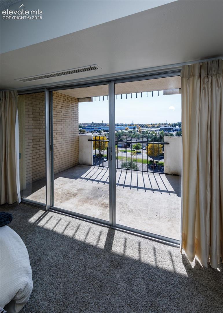 Private balcony featuring a concrete floor, light-colored brick wall, and metal railing with expansive exterior scenery