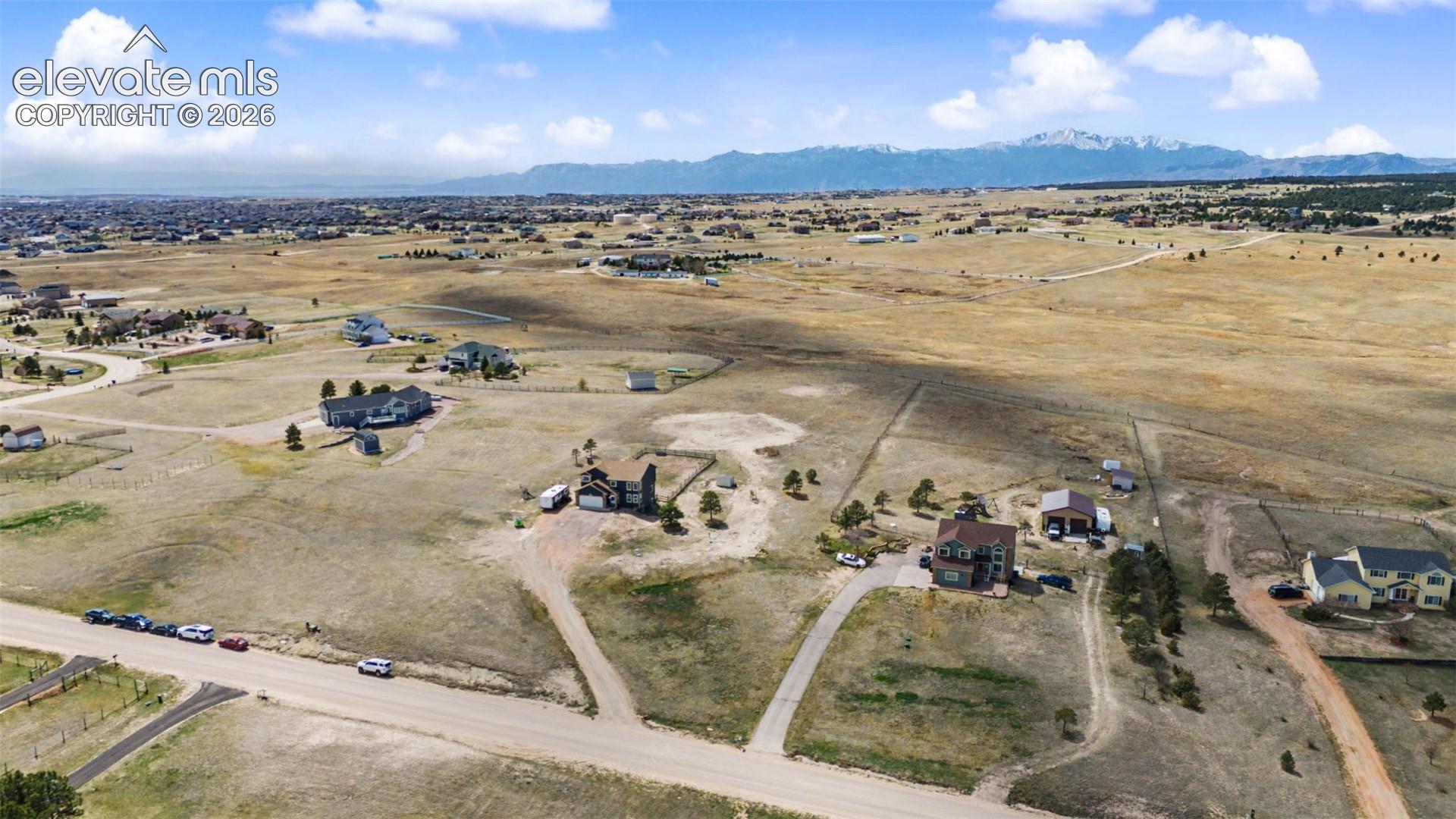 Aerial perspective of expansive acreage featuring gravel road access and unobstructed mountain range scenery