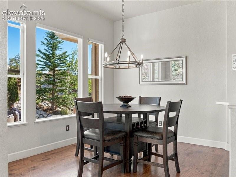 Dining area bathed in natural light through expansive multi-pane windows framing mature evergreen landscaping