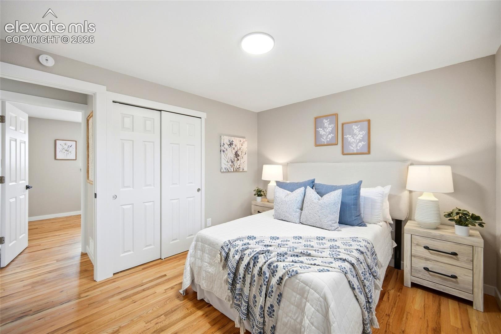 Hardwood flooring, painted walls, white trim, flat panel ceiling light, and sliding closet doors