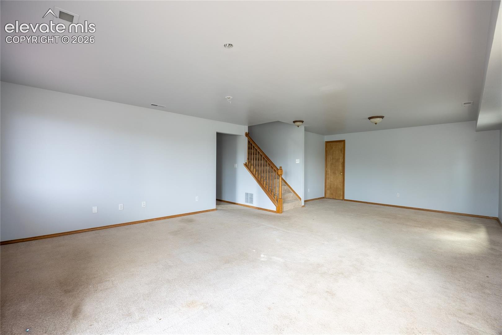Expansive carpeted area with neutral wall tones and recessed lighting