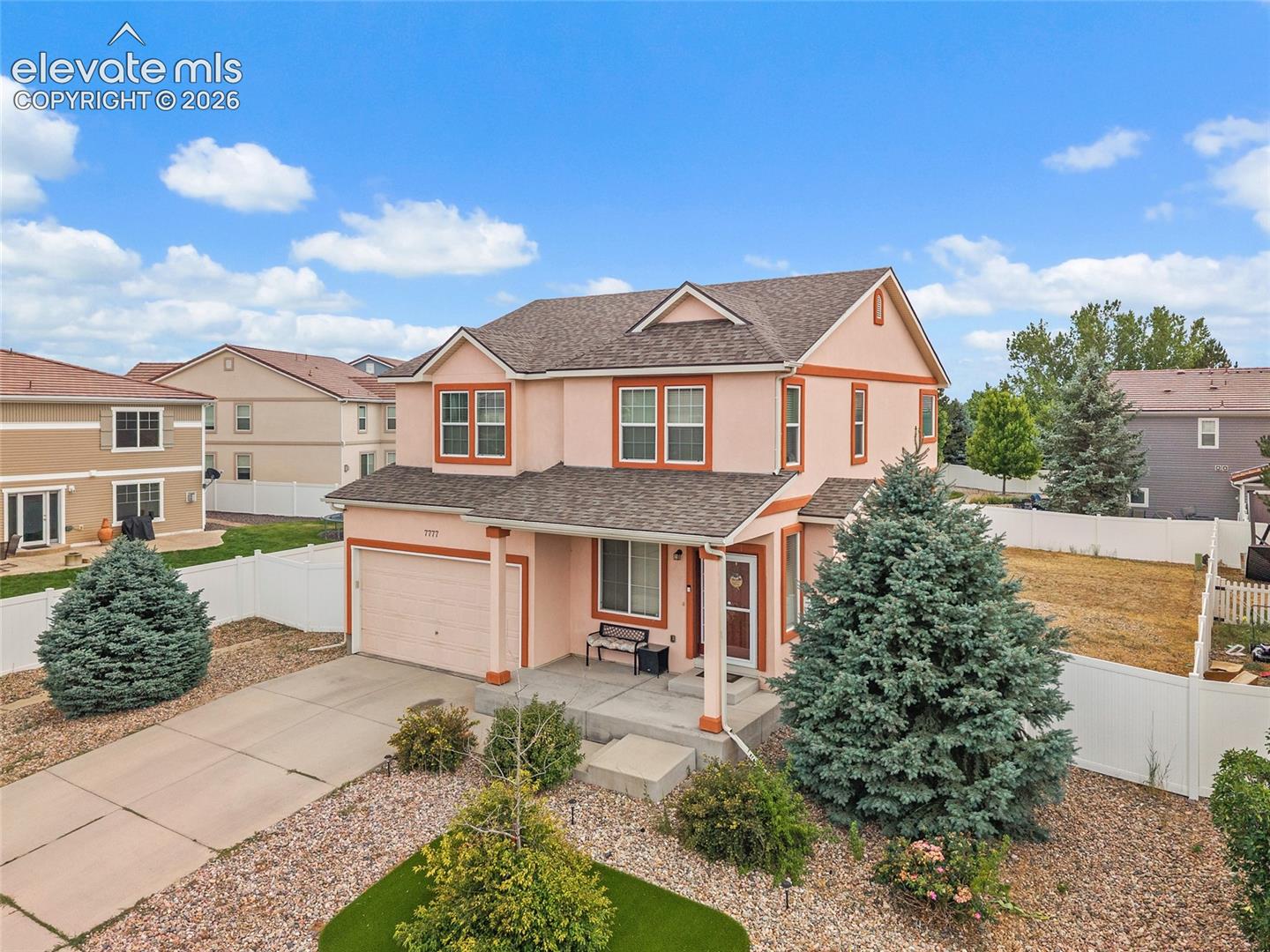 Two-story residence featuring a covered front porch, attached two-car garage, and low-maintenance landscaping with decorative rock beds