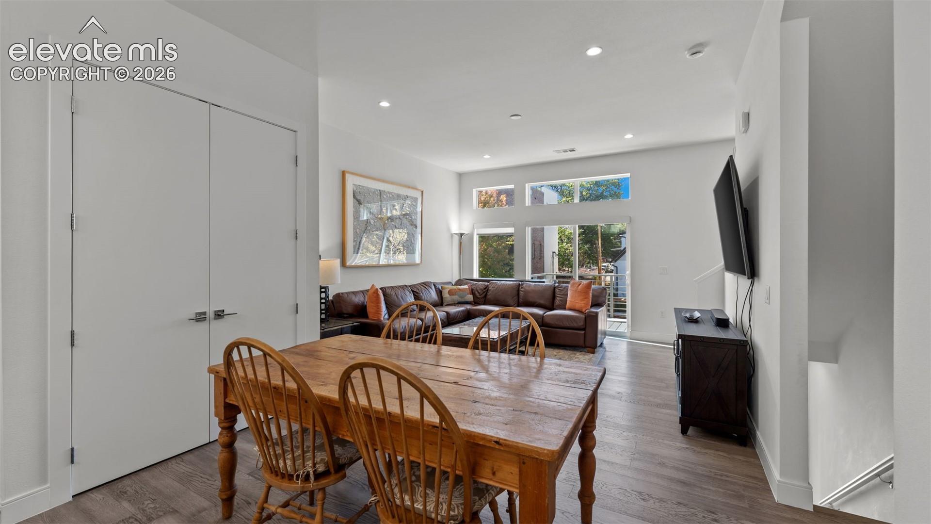 Open-concept interior featuring wood-finish flooring, recessed lighting, double-door closet, and large windows with transom panels