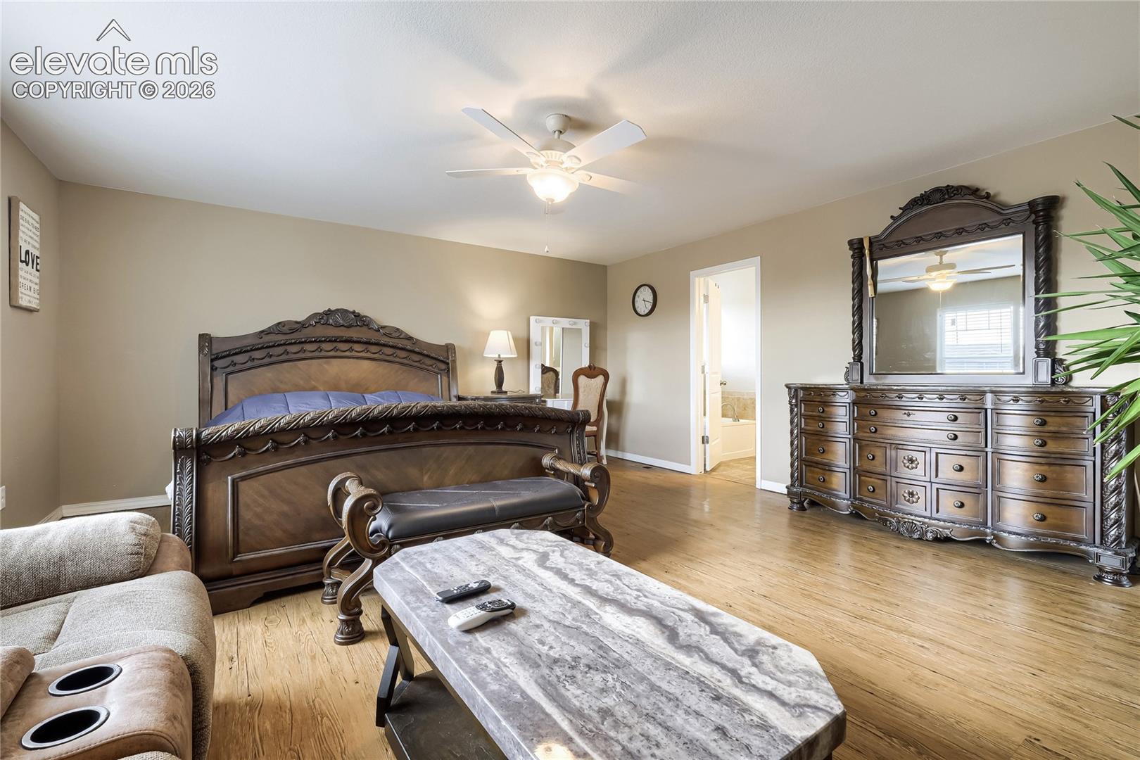 Primary bedroom featuring wood-finish flooring, a sitting area and large walk-in closet and 5 pc bath