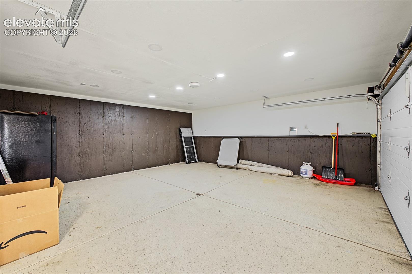 Attached garage featuring a concrete floor, recessed lighting, and an automatic garage door