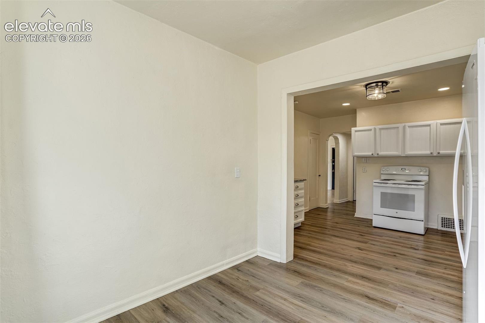 Wood-finish flooring, white cabinetry, recessed lighting, and a flush-mount ceiling fixture
