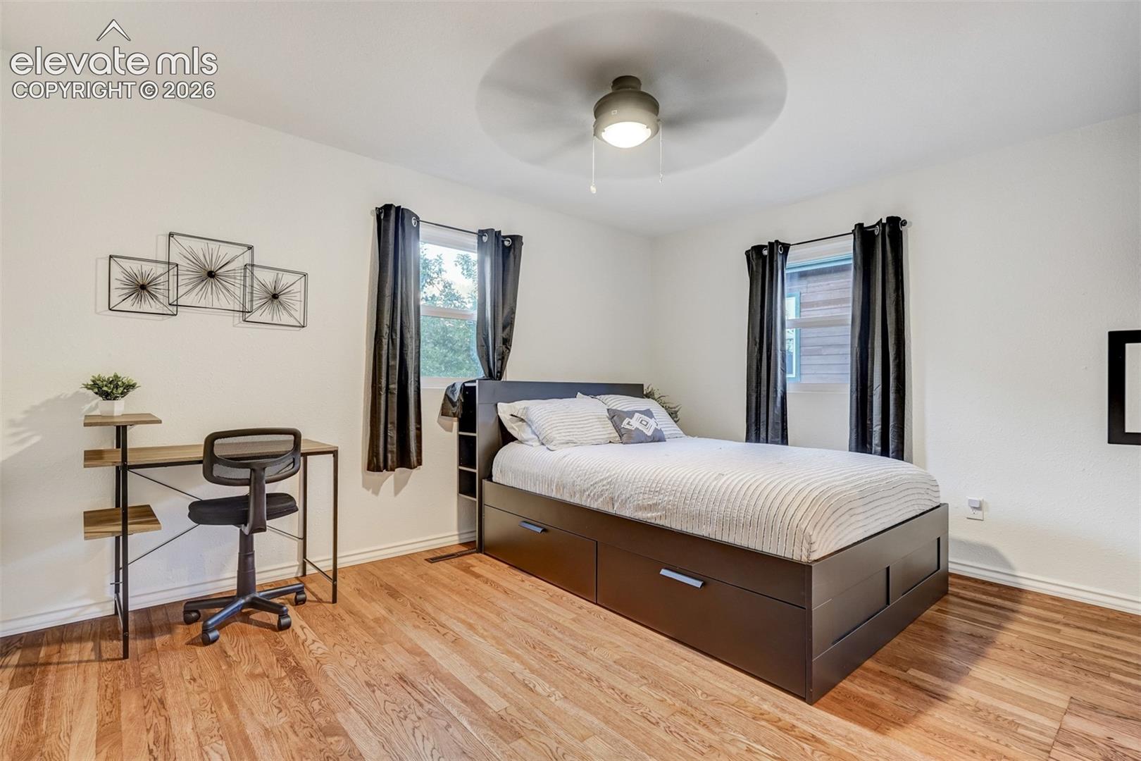 Wood-finish flooring, white walls, and a ceiling fan with integrated lighting