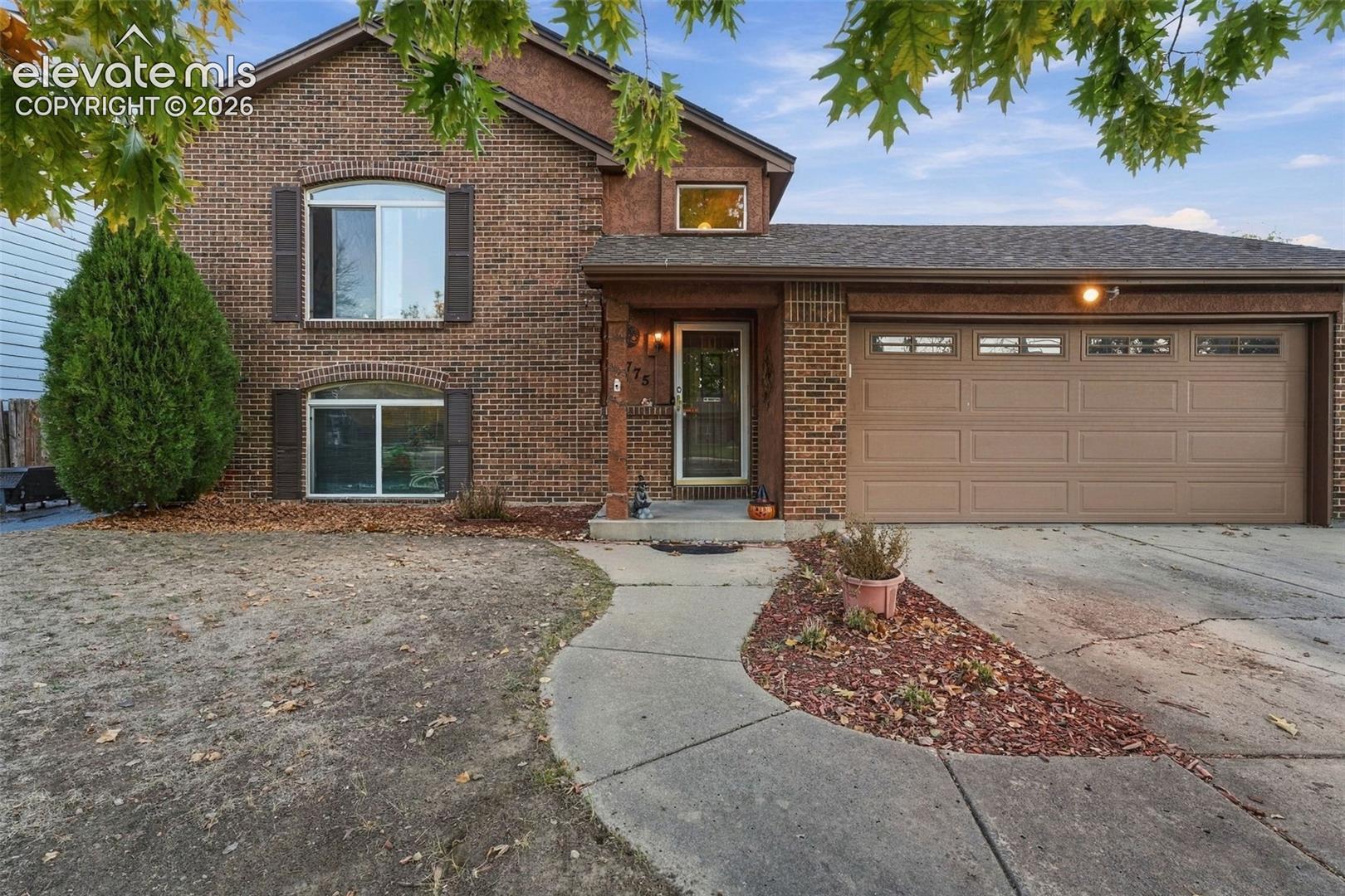 Brick exterior residence featuring a multi-level roofline, arched window casings, and an attached two-car garage