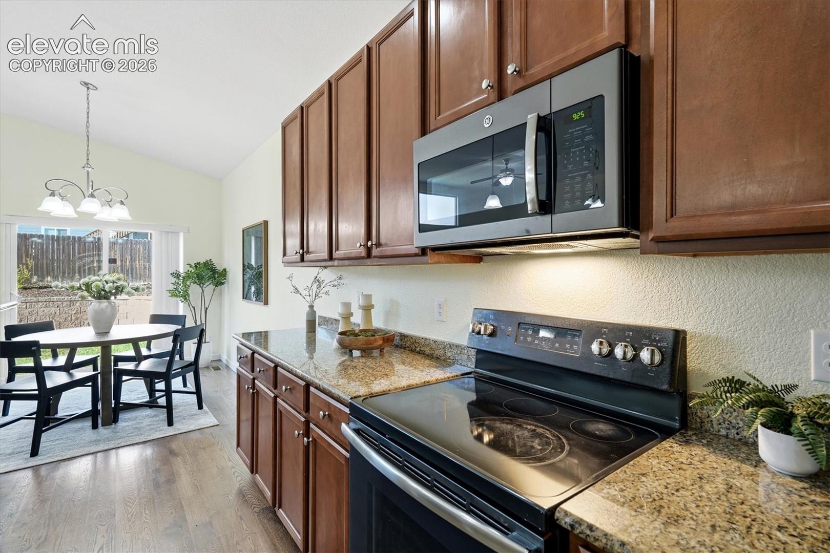 Kitchen featuring wood-finish cabinetry, granite countertops, and stainless steel microwave