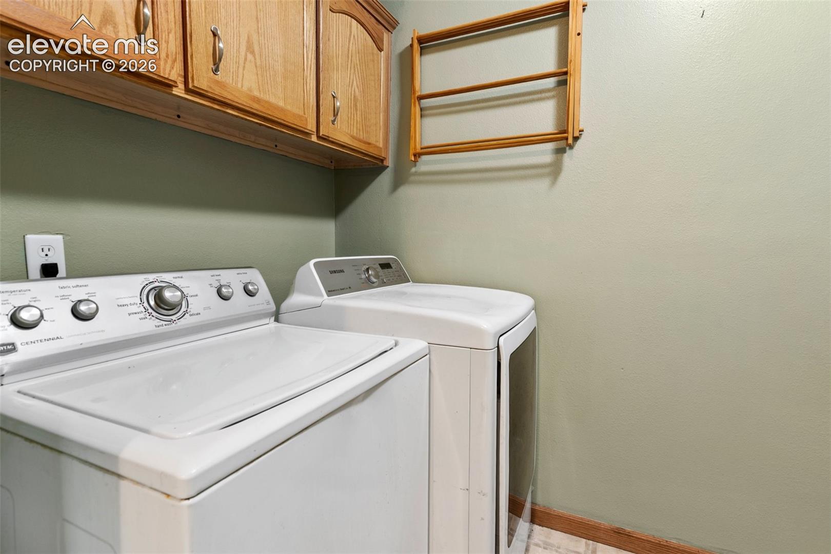 Dedicated utility space featuring overhead wood cabinetry and light green painted walls