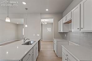 kitchen with center island, undermount sink, white cabinetry, and pendant lights over the island