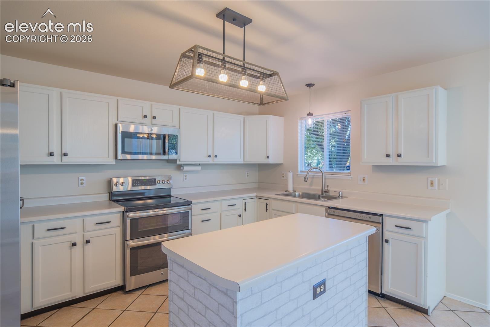 Generous cabinetry and counter space, complemented by stainless steel appliances and statement pendant lighting.