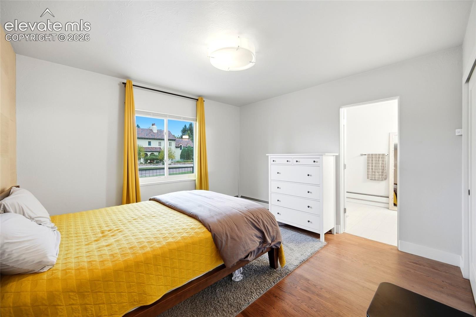 The primary bedroom has an ensuite bath, hardwood floors, and views of the elegant Broadmoor neighborhood outside. 