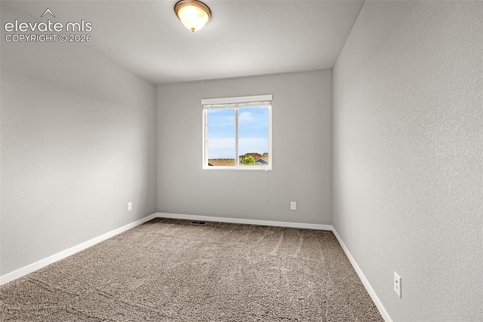 Neutral wall paint, plush carpet flooring, and a single window with blinds