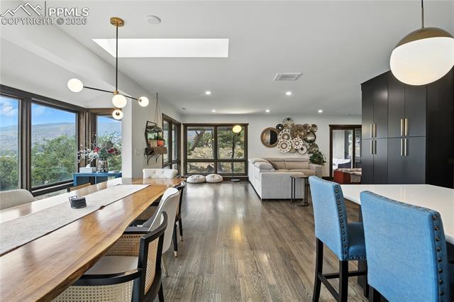 Dining room with a skylight, dark wood finished floors, and recessed lighting