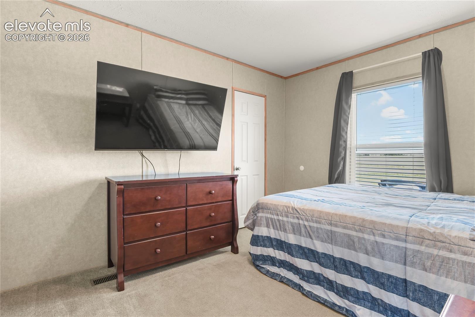 Interior room featuring neutral wall paneling, carpeting, a single-panel interior door, and a window with horizontal blinds