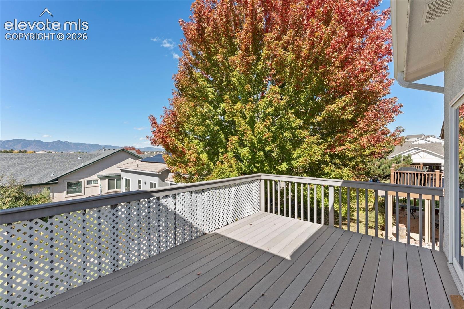 Elevated deck featuring composite decking, white lattice railings, and mountain background scenery