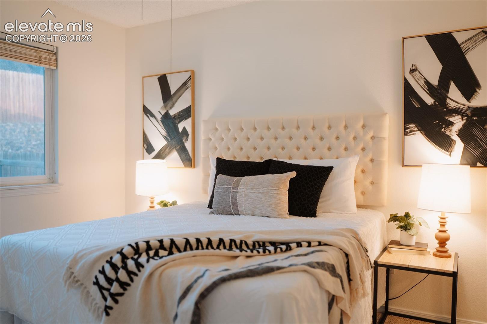 Neutral-toned interior space featuring a single window with slatted wood blinds and textured wall-to-wall carpeting